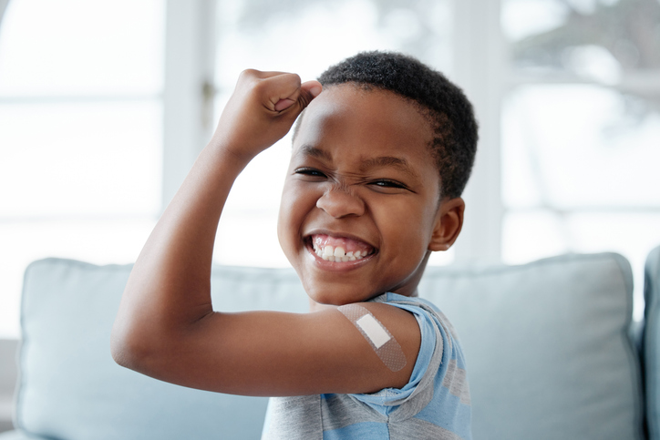 Smiling boy with a bandaid on his arm after vaccine injection